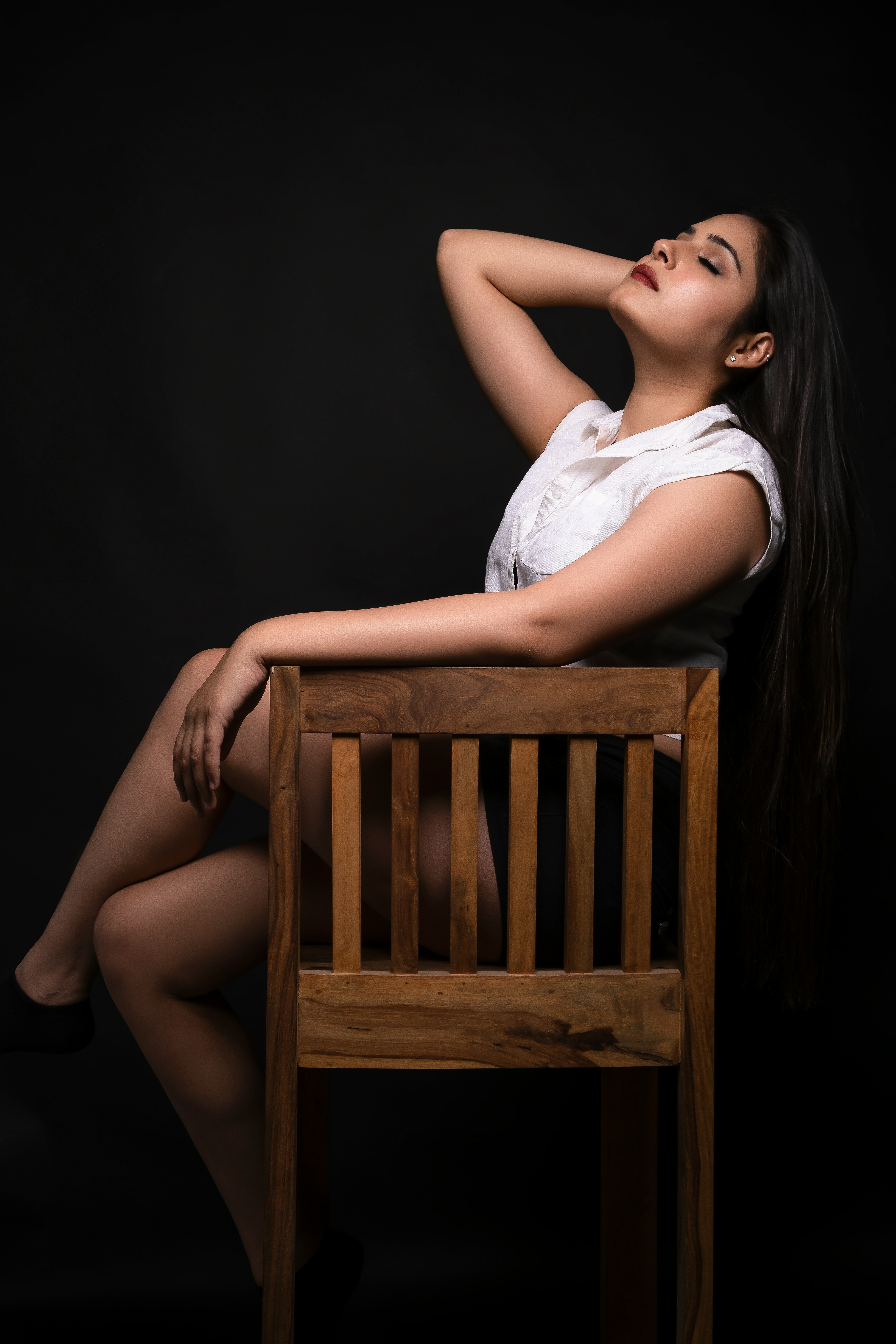 woman in white sleeveless dress sitting on brown wooden chair